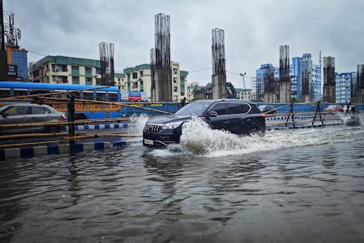 Flooded street scene in Kolkata with vehicles navigating heavy monsoon rainwater. Urban landscape during rainy season.